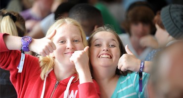 Children smiling with thumbs up.